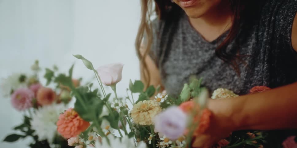 Woman arranging flowers in a pot on the living room