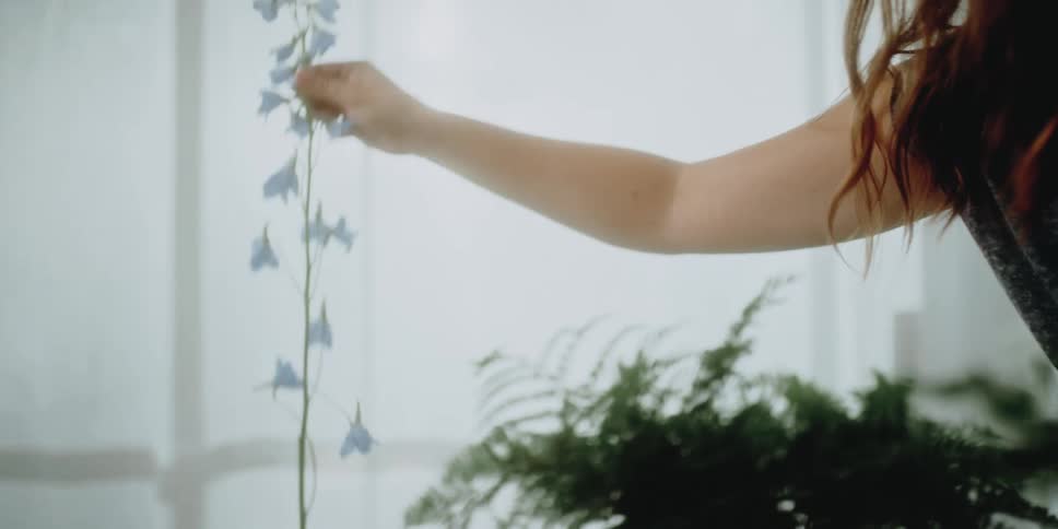 Smiling woman puts together flower arrangement