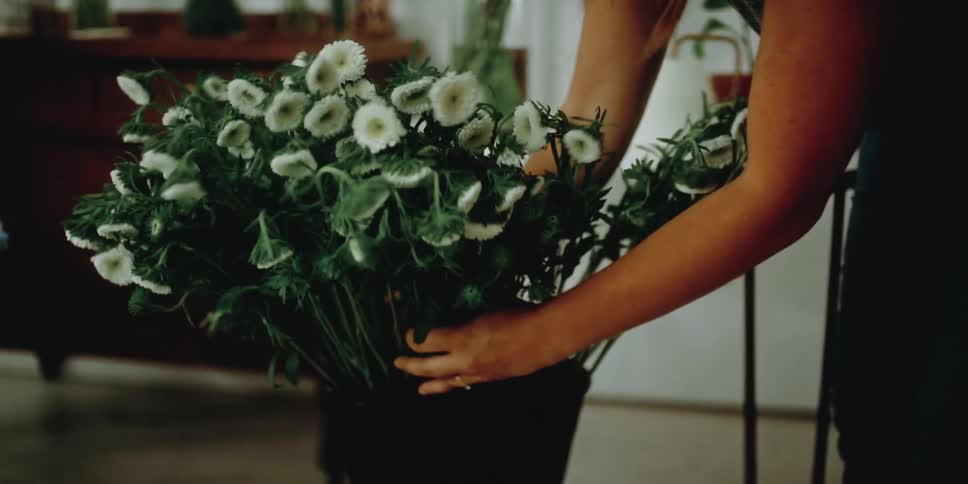 Woman placing a flower arrangement on a table in the living room