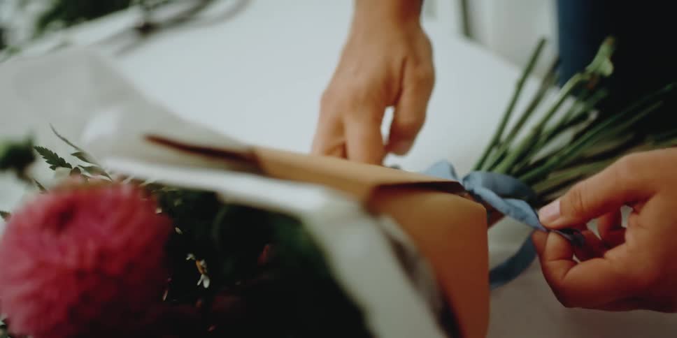 Woman finishing a flower arrangement with a blue handmade bow