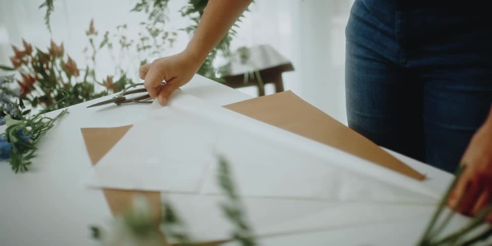 A woman folding paper in a floral shop