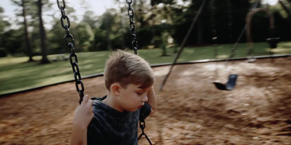 Boy swingin on a playground in a park