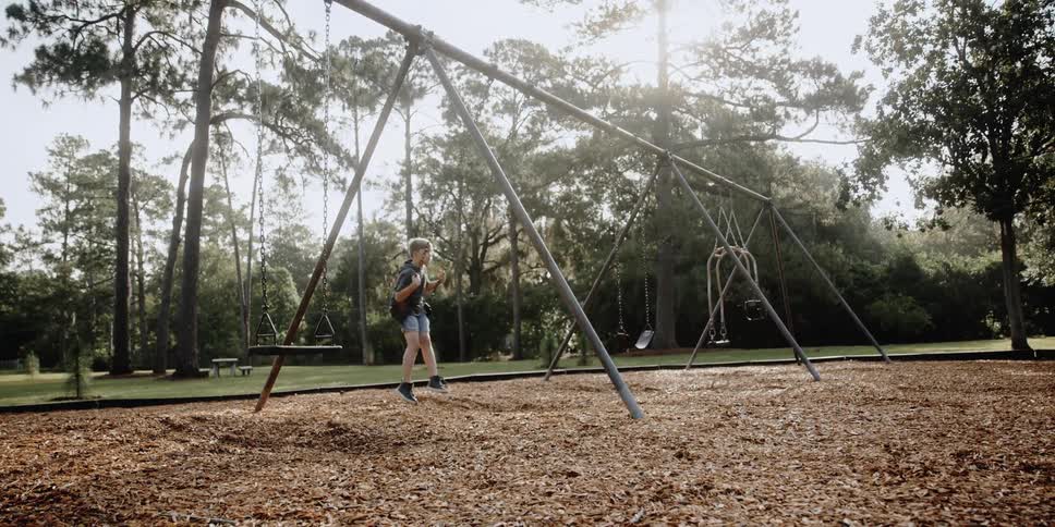Young boy swinging in a playground on the park at daytime