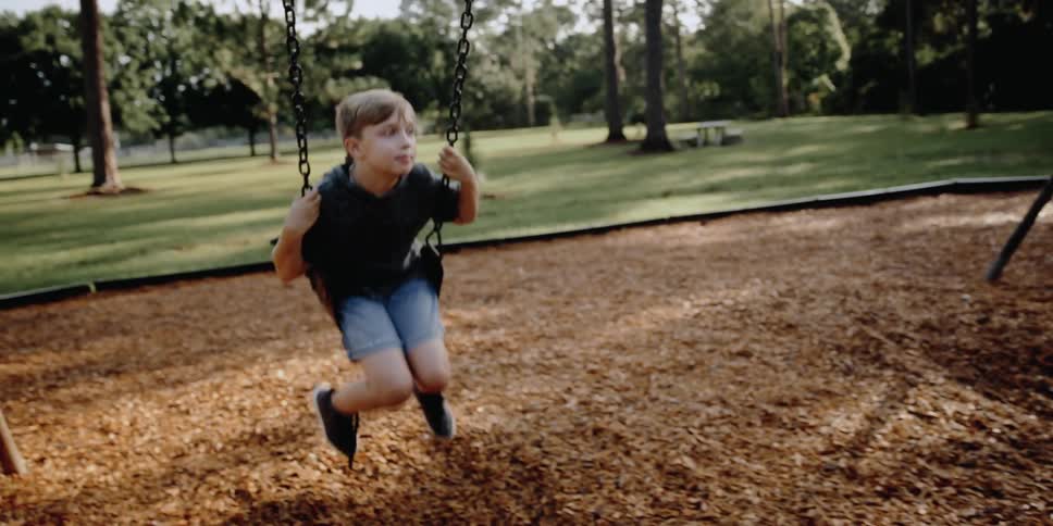 A boy is swinging outdoors at a playground