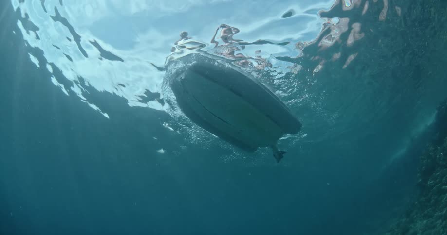 A diving boat is moving across the ocean surface in daylight