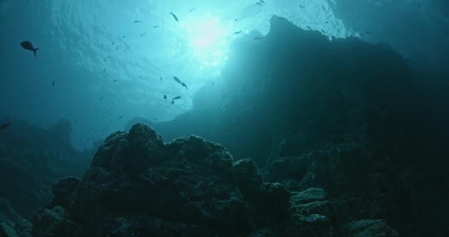 The sun is shining behind the rocks in the dark waters