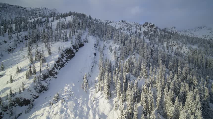 Dynamic orbit around a sun kissed and snow covered mountainside
