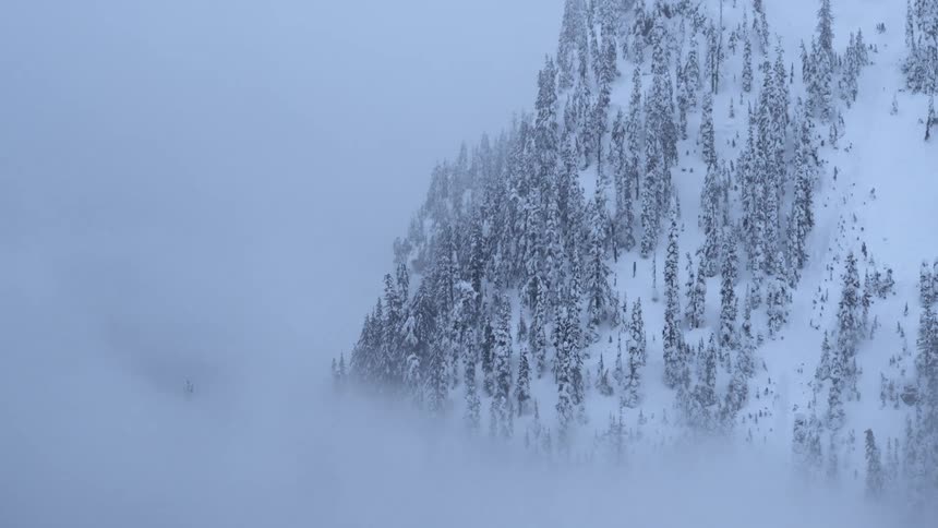 A steep mountainside ridge peeks out from behind dense morning fog