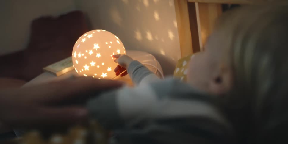 Mother strokes childs arm as child reaches for star covered glowing ball