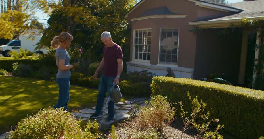 A man and woman watering in a garden