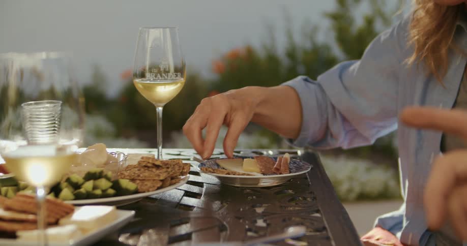 A woman sitting next to a man at a table with wine puts food on her plate