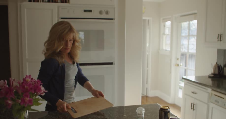 A woman getting a cutting board out of a cabinet