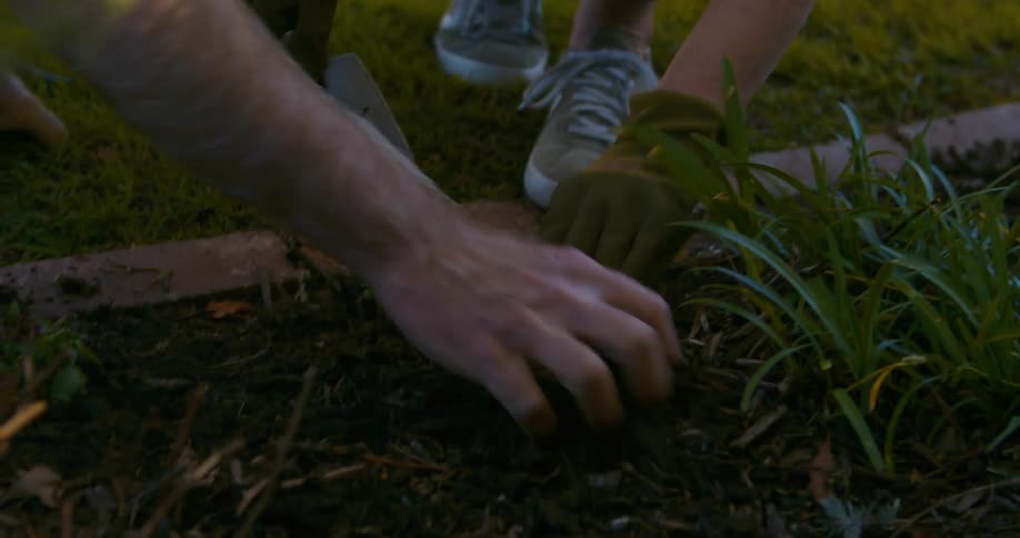 A man and his son are working in a flower bed with a shovel