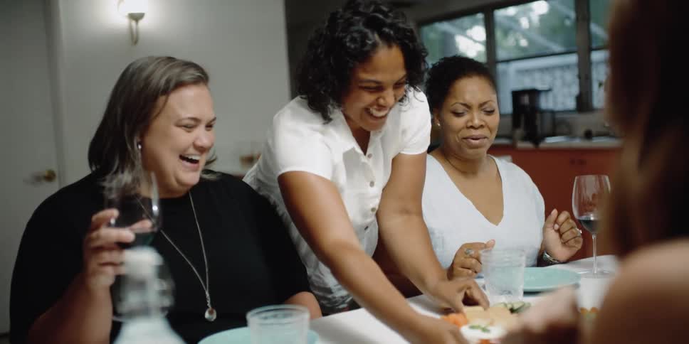 Group of happy friends drinking wine and eating in the dinner table at home