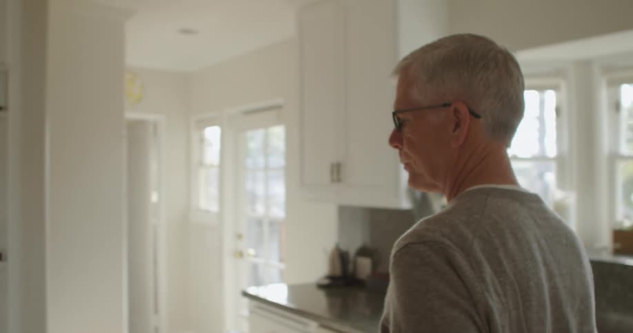 A man carries a tablet around a kitchen oven to show his wife the display