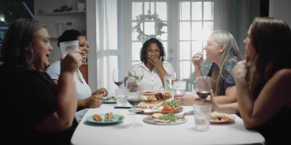 Group of happy friends laughing and talking over dinner at home