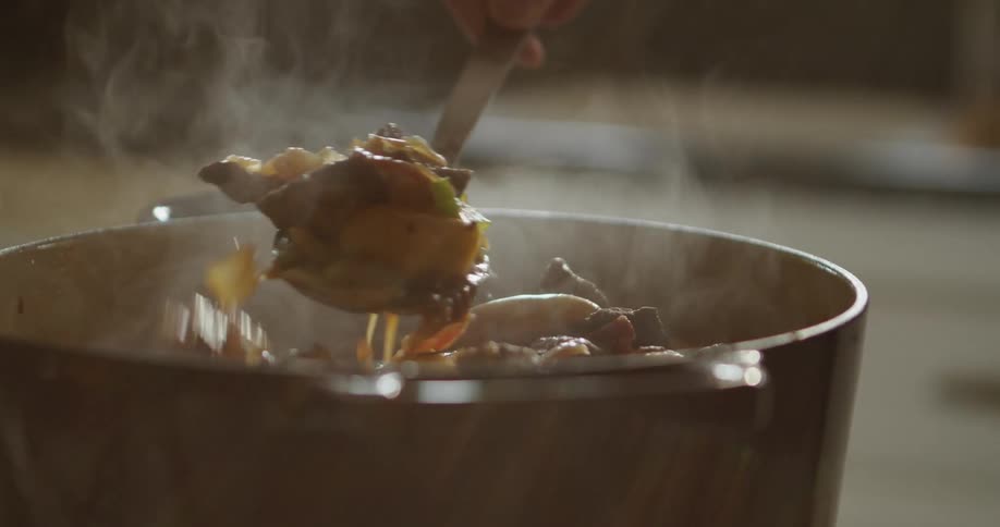 A person is stirring food and cooking it
