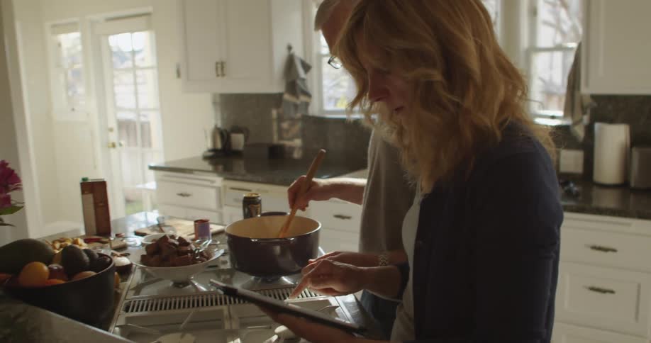 A man and woman cooking food in a kitchen together