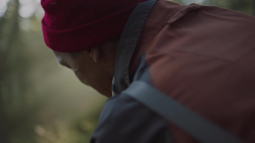 A man sits in a forest with his head bowed down