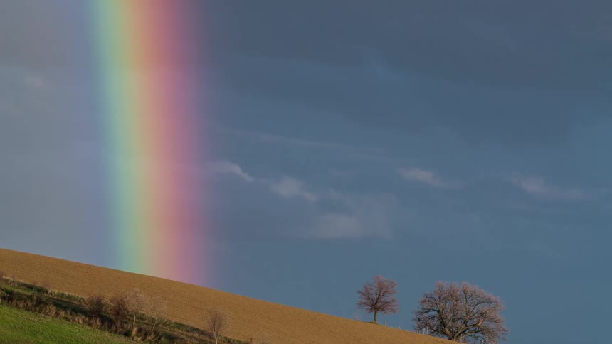 A rainbow in the sky over a hill