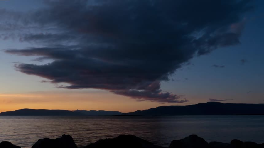Time lapse of clouds floating over a lake at sunset