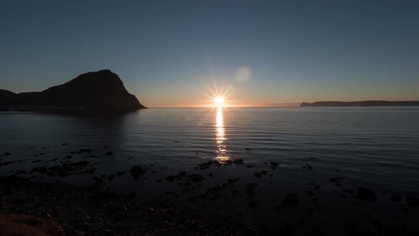 Sun setting over the water in a clear blue sky