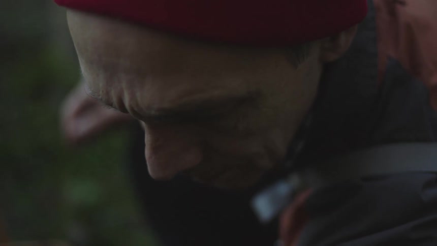 A man looks down as he forages in the forest
