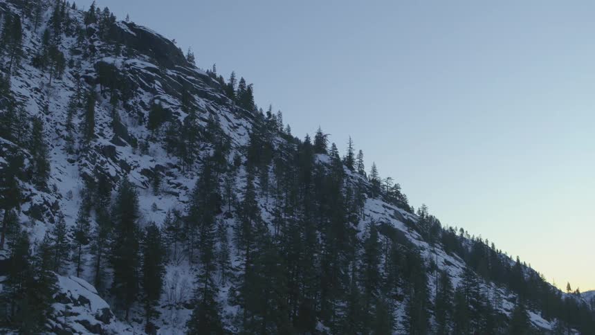 Pine and fir trees line a steep and rocky mountainside