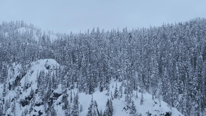 Traverse above a snow covered mountain ridge on a gray winter day
