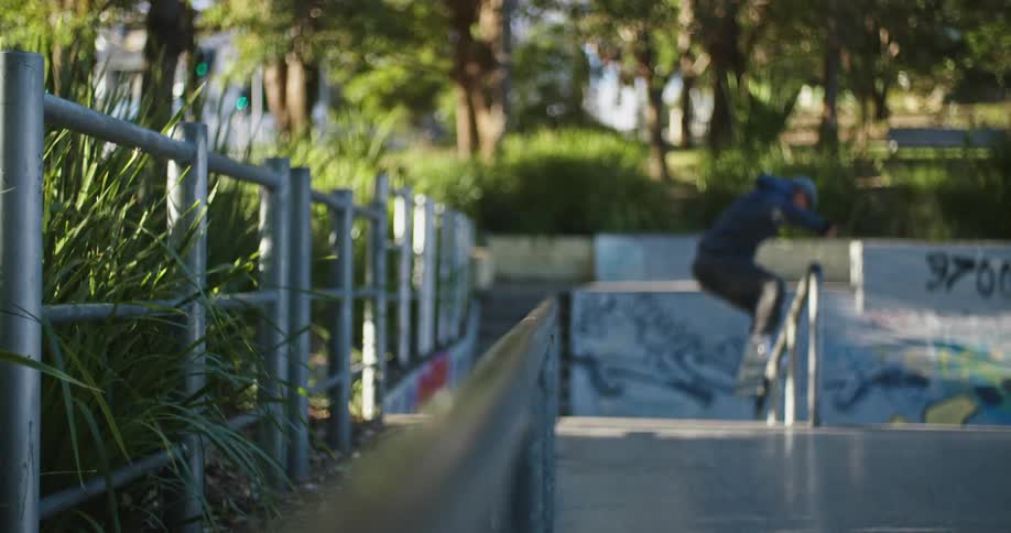 A man is roller blading down a rail at a park in spring