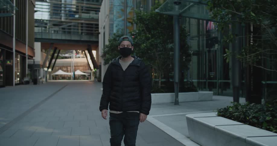Man wearing a black face mask rides a skateboard in the city
