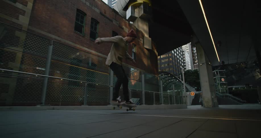 A man riding a skateboard with buildings an overpass the sky and clouds in the background