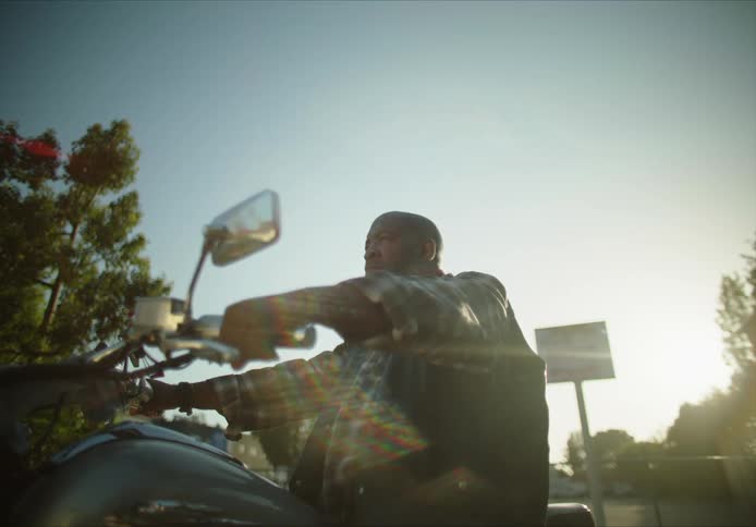 A man is sitting on a motorcycle at dusk