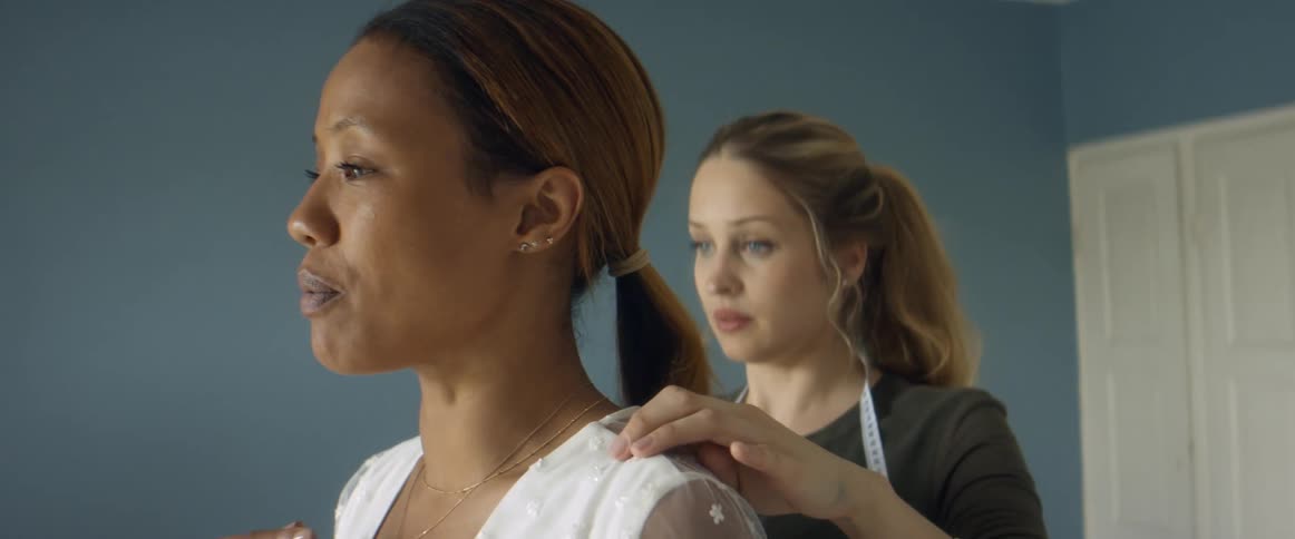 Two women are standing in a room and talking