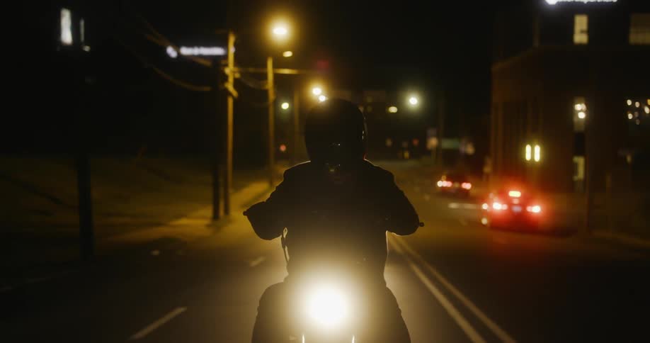 A person is driving a motorcycle in a city at night