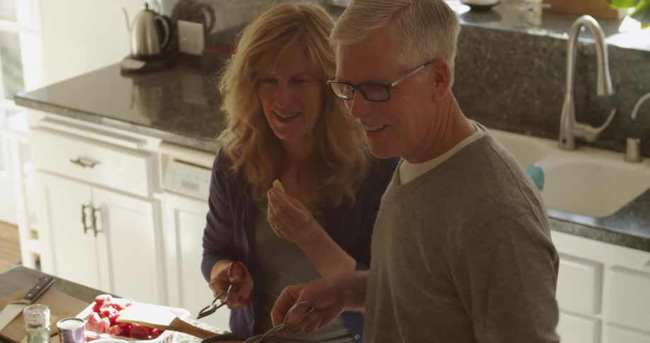 Husband and wife are cooking food together in their kitchen