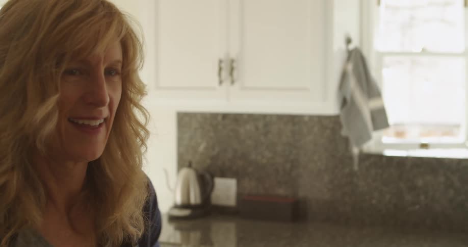 Blonde woman smiling while cutting potatoes on a wood cutting board