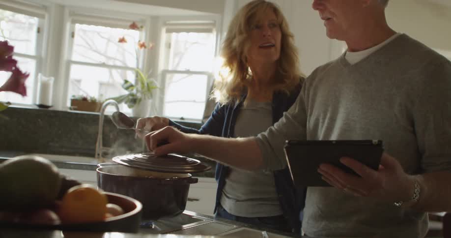 Husband and wife are cooking dinner together in their house