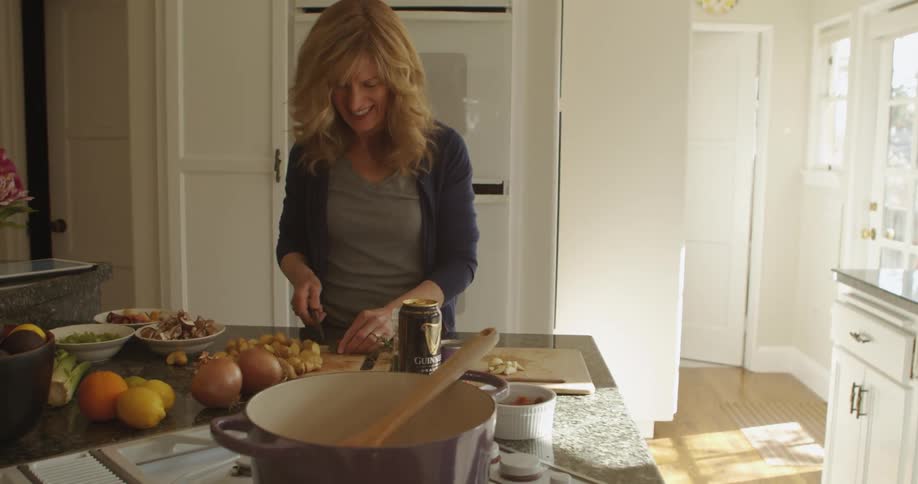 A man and woman are in a bright kitchen chopping vegetables