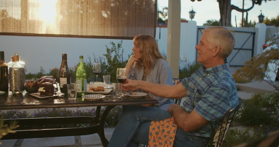 Two men and two women sit at a table with bottles glasses and plates