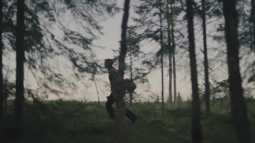A man is hiking through a forest at dusk