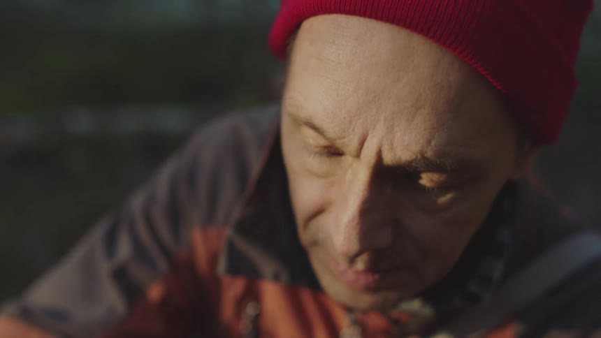 Man picks a mushroom and holds it in his fingers and looks at it