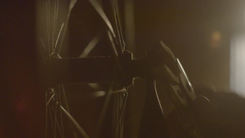 A hand using pliers to adjust a bolt on a wheel indoors