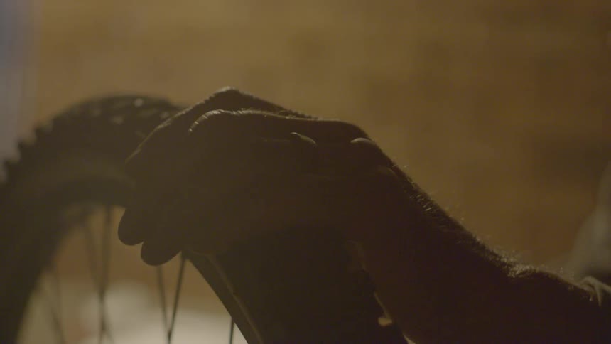 A man is cleaning a bicycle tire indoors