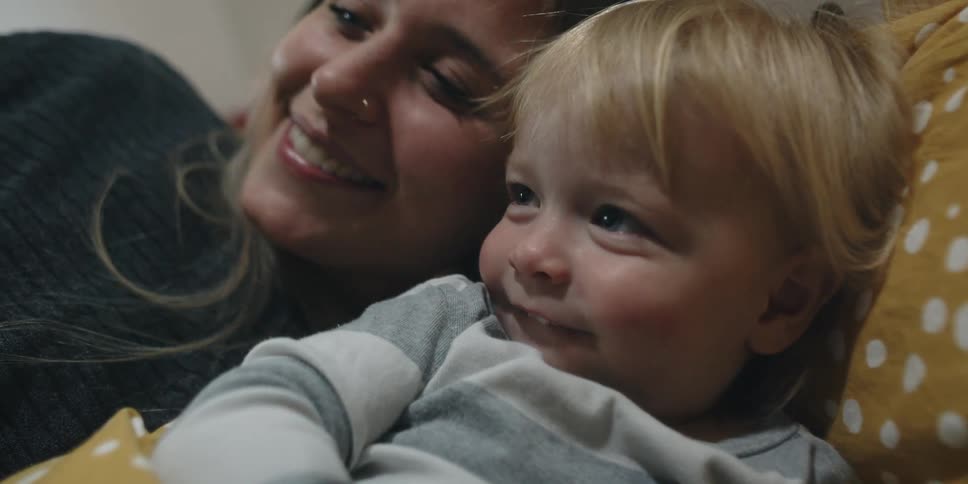 Mother kisses her son forehead while resting in bed at home