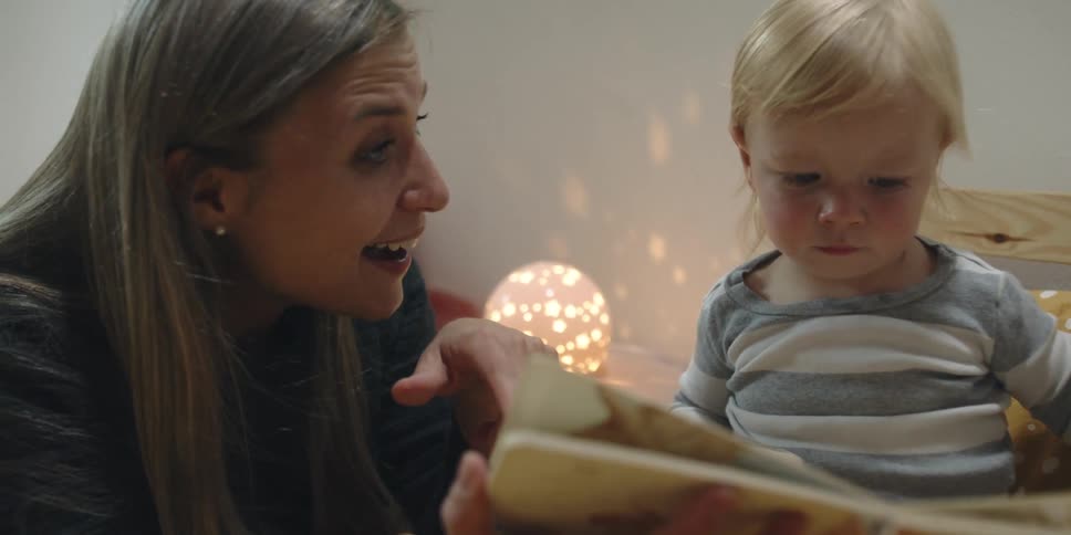 A woman reads to her young child in bed