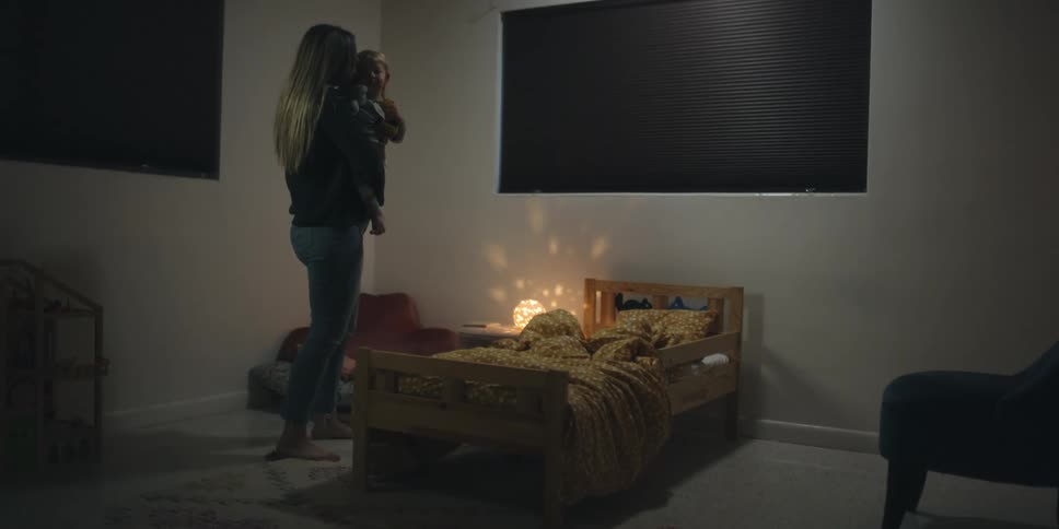 Mother kissing and holding her son in the dimly lit bedroom