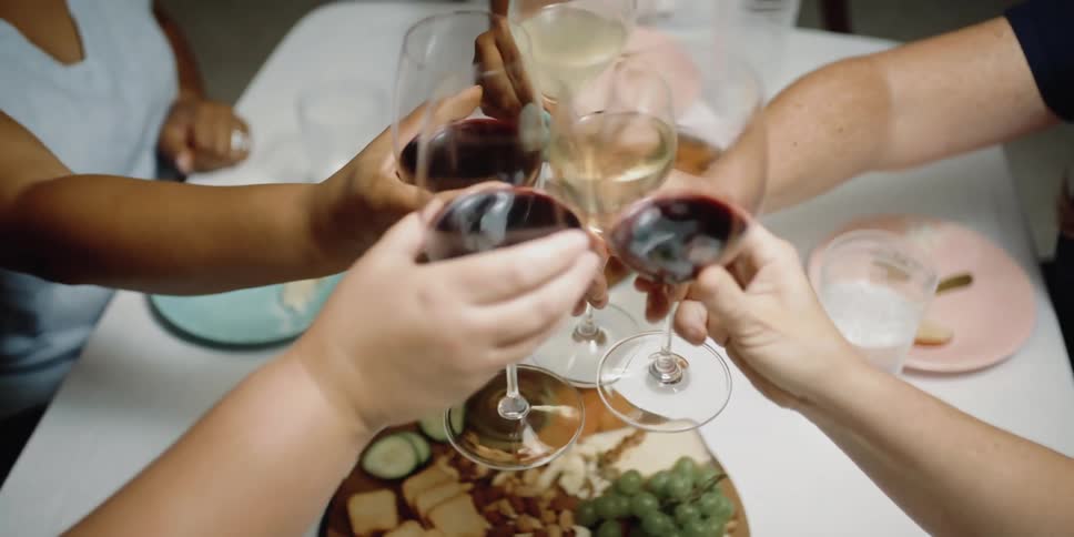 A group of friends are drinking wine and eating dinner together