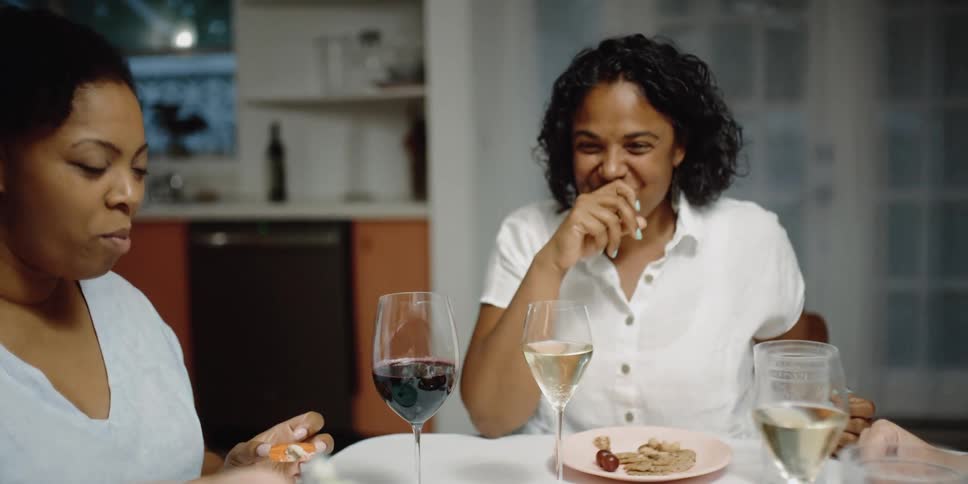 A group of women sitting at a table eating and laughing amongst one another