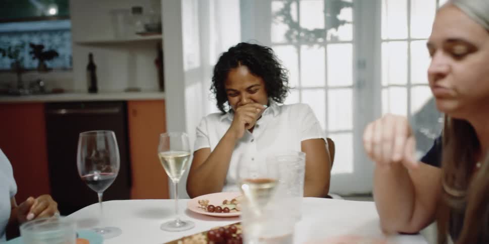 Group of friends talking and laughing over dinner at home